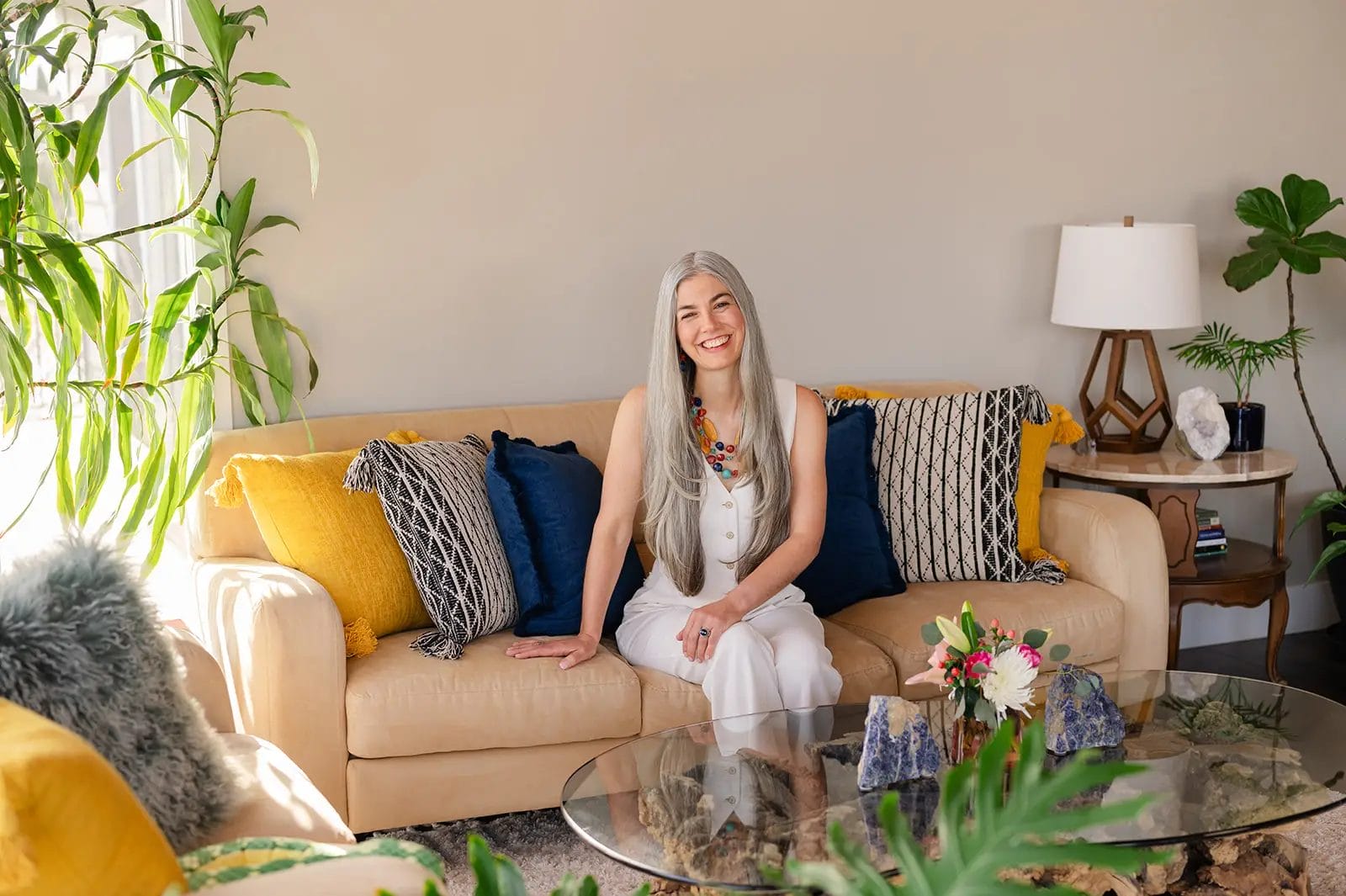 Emily Paul sitting on a couch smiling in her living room.